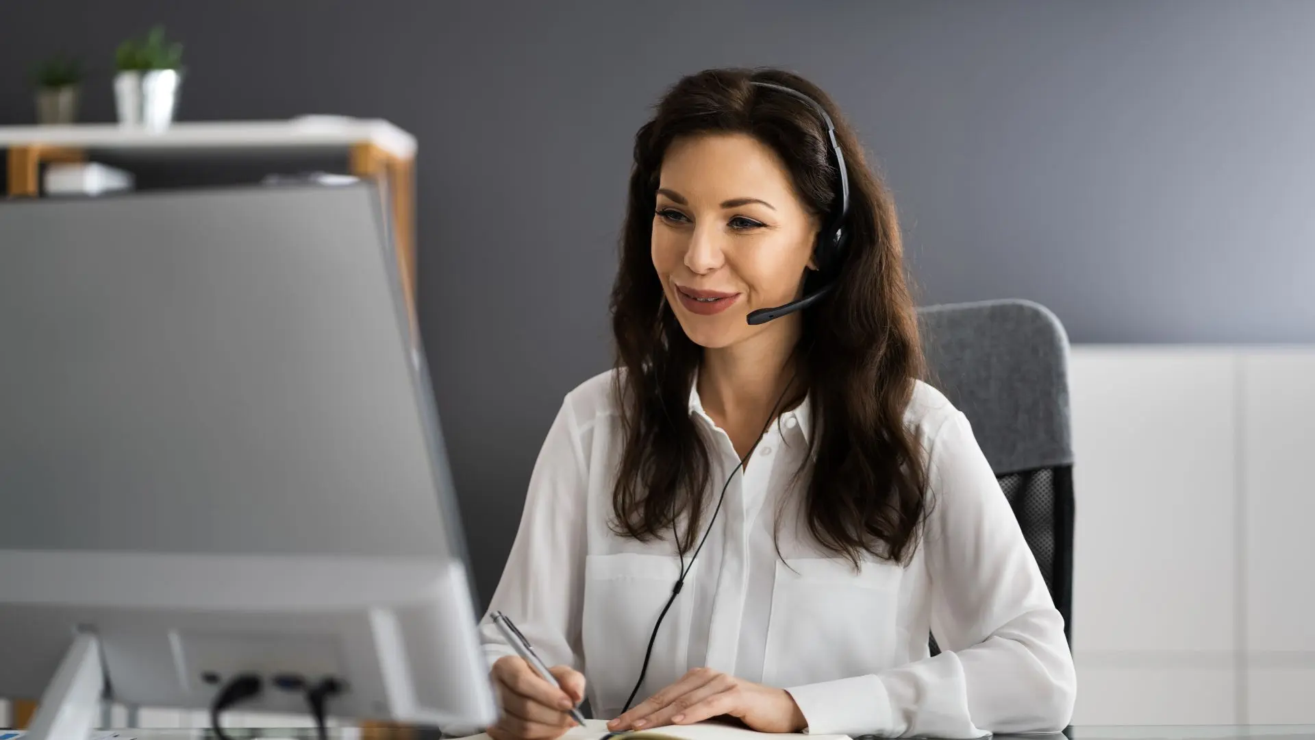 Mujer con auriculares y micrófono frente a ordenador hablando de traducción para doblaje de videos de productos