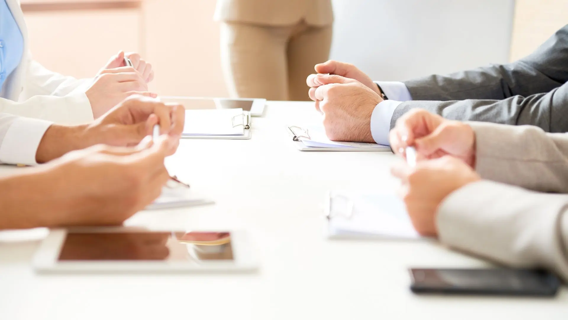Cuatro personas en una mesa con tablets y portapapeles teniendo una reunión sobre la interpretación de enlace