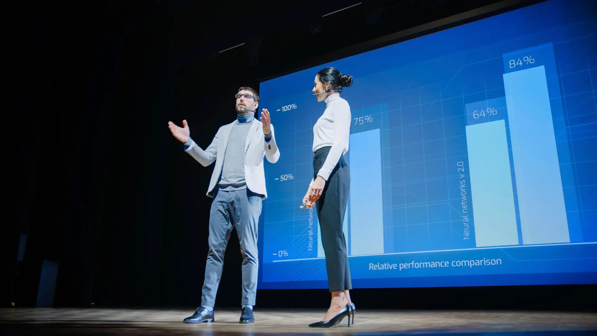 Mujer y hombre dan conferencia sobre la importancia de la interpretación de idiomas en la comunicación global frente a una pantalla azul con gráficos