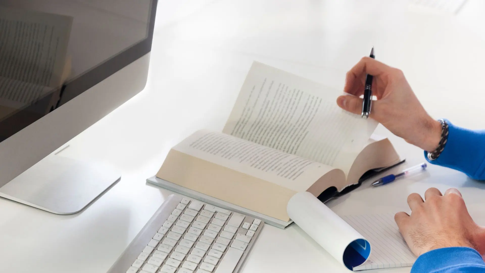 Hombre pasa la página de un libro sobre un traductor jurado italiano y apunta en su libreta frente a su ordenador