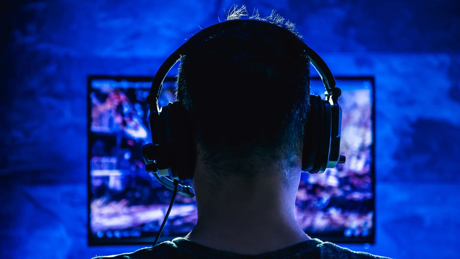 Hombre con auriculares y micrófono jugando al ordenador sobre traducción y localización de videojuegos