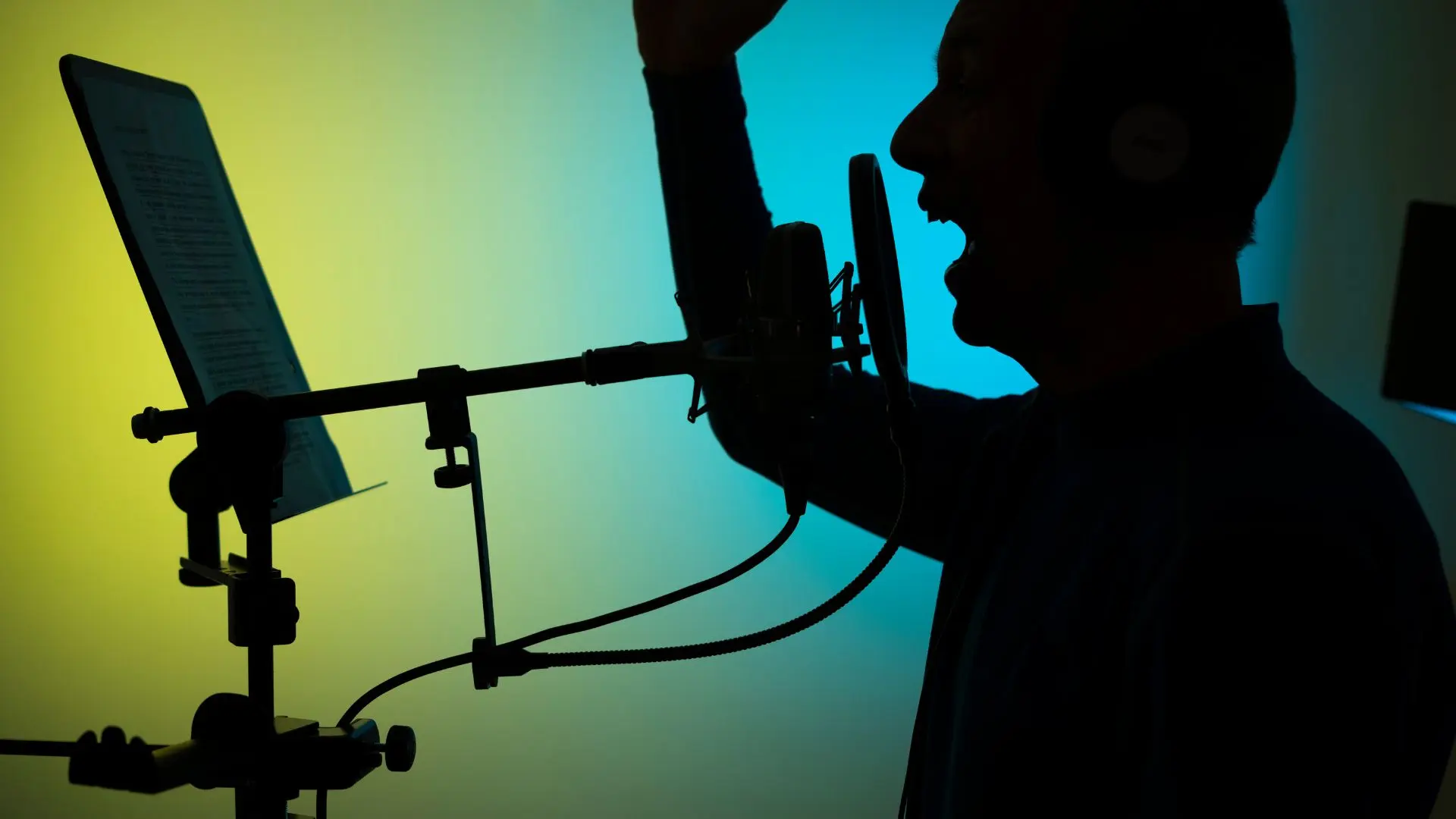Hombre hablando frente a un micrófono en un estudio de grabación con un guion sobre doblaje de videojuegos