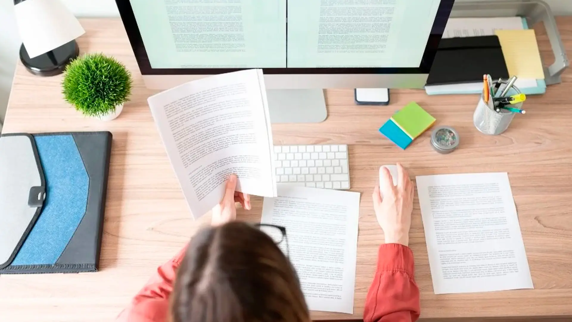 Mujer con gafas trabajando en su ordenador en un escritorio leyendo un documento sobre herramientas de traducción ideales para hacer traducciones