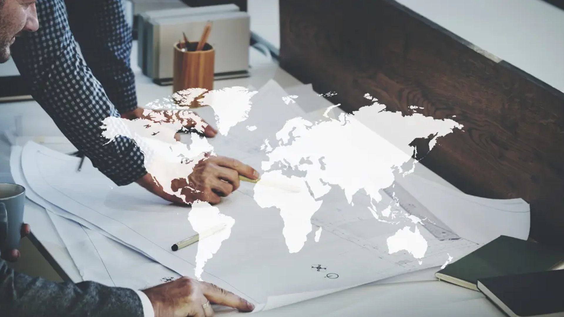 Dos personas apoyadas en una mesa en la que hay un mapamundi hablando sobre los idiomas más demandados en el mundo laboral