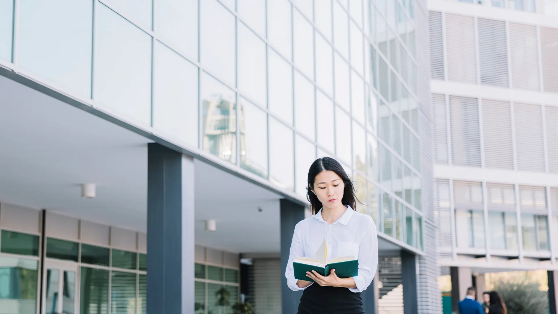 Mujer leyendo un libro sobre negociar en china y traductor chino a español frente a un edificio