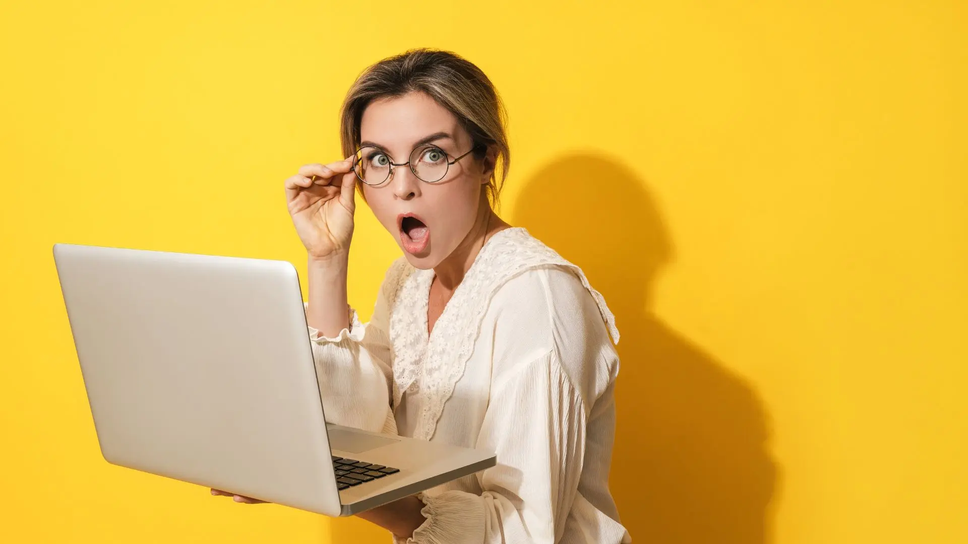 Mujer con gafas sorprendida sujetando un ordenador leyendo sobre traducir neologismos