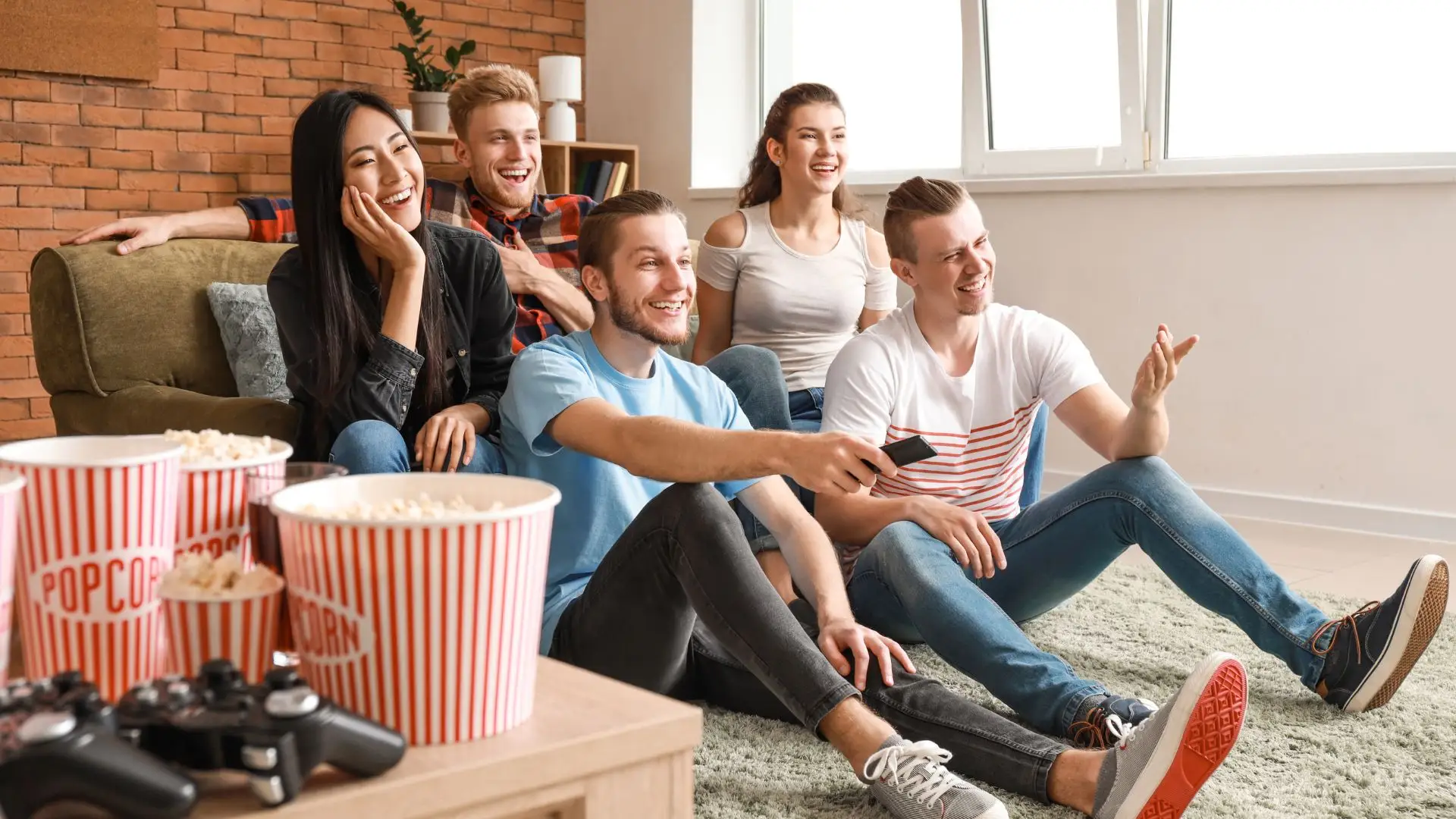 Cinco personas sentadas en un sofá sonriendo viendo en la televisión sobre las ventajas de poner subtítulos en español a tus vídeos