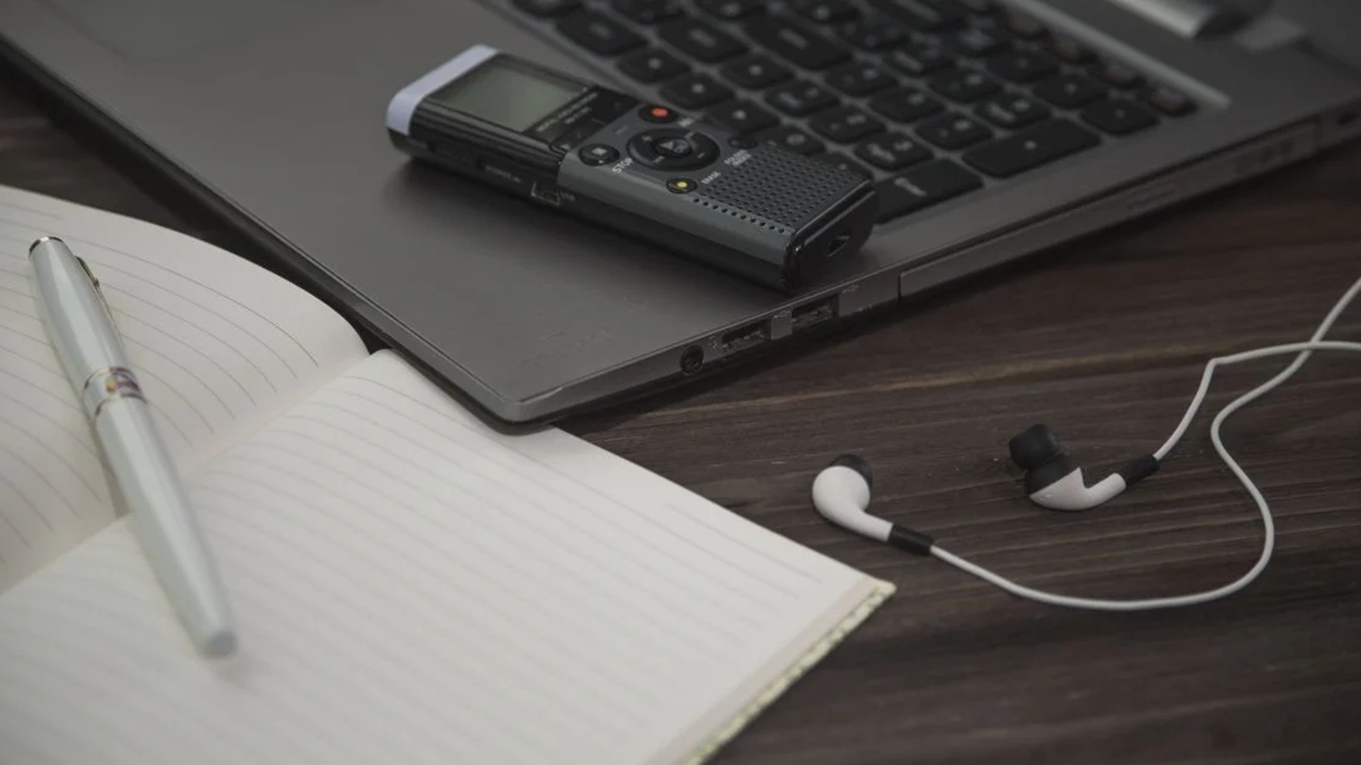Libreta, bolígrafo, cascos y grabadora para transcribir audio a texto