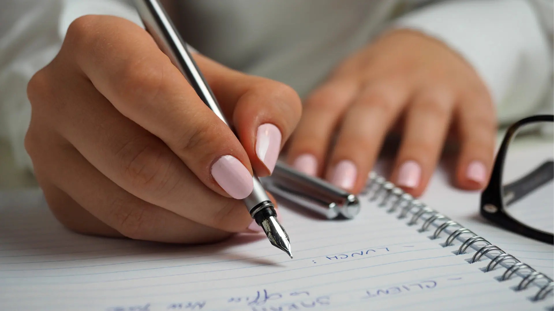 Mujer escribiendo con bolígrafo en una libreta sobre proofreading y revisión de traducciones