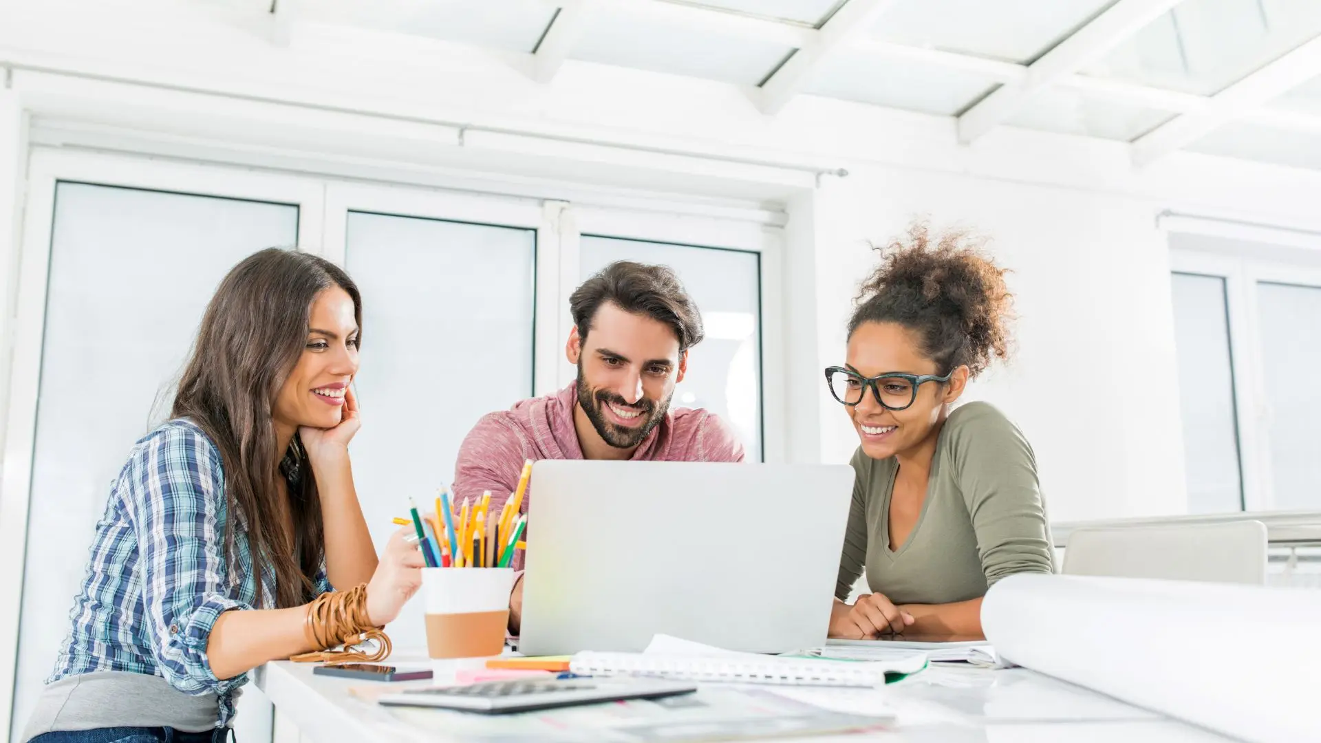 Tres personas frente a un portátil en una reunión sobre una web multilingüe