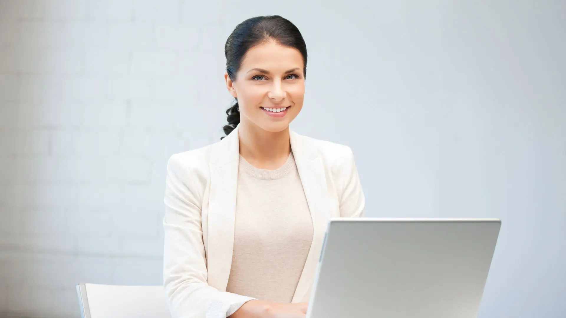 Mujer con portátil escribe sobre los requisitos que debe cumplir un traductor e intérprete